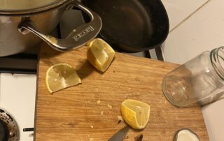lemon cut up near a chopping board with knives ETC